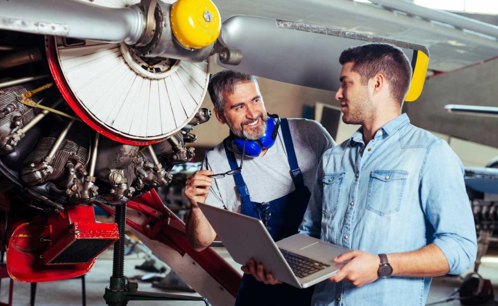 Engineer looking at laptop for maintenance an airplane.