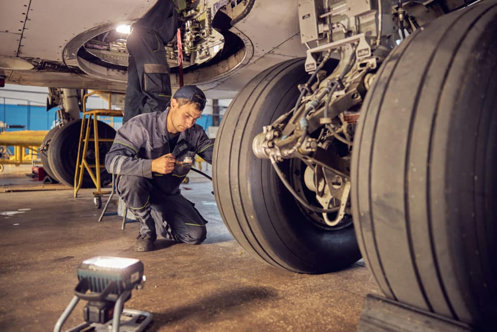 Close up portrait of ground crew working at the airport fixing airplanes and checking the landing gear